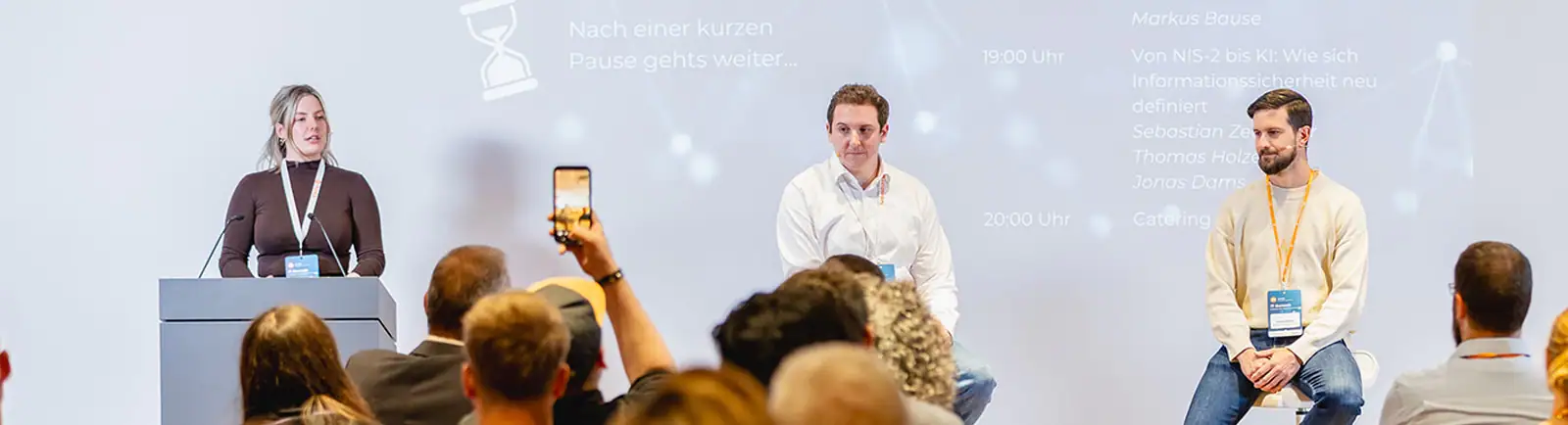 Podiumsdiskussion beim mITSM IT-Summit mit drei Sprechern vor Publikum.
