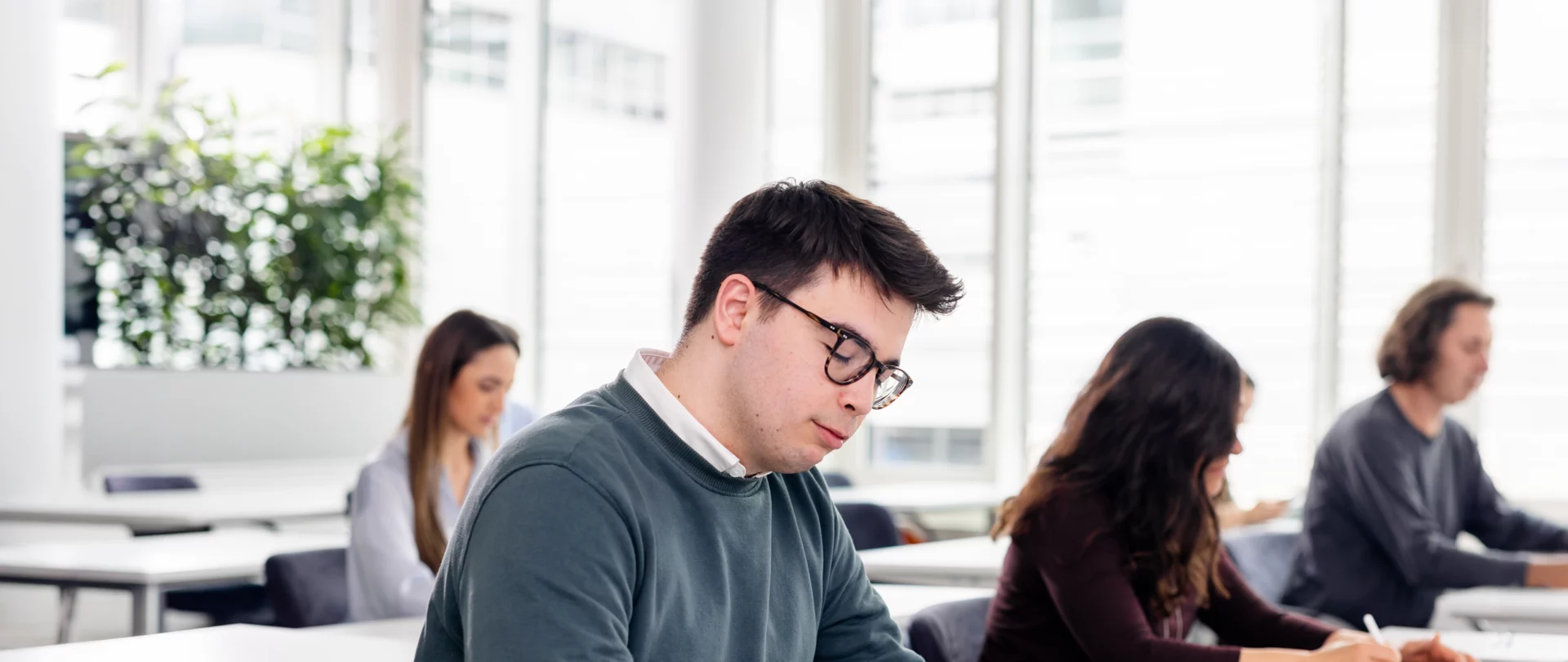 Junge Menschen lernen in einem modernen Schulungsraum mit Laptops.